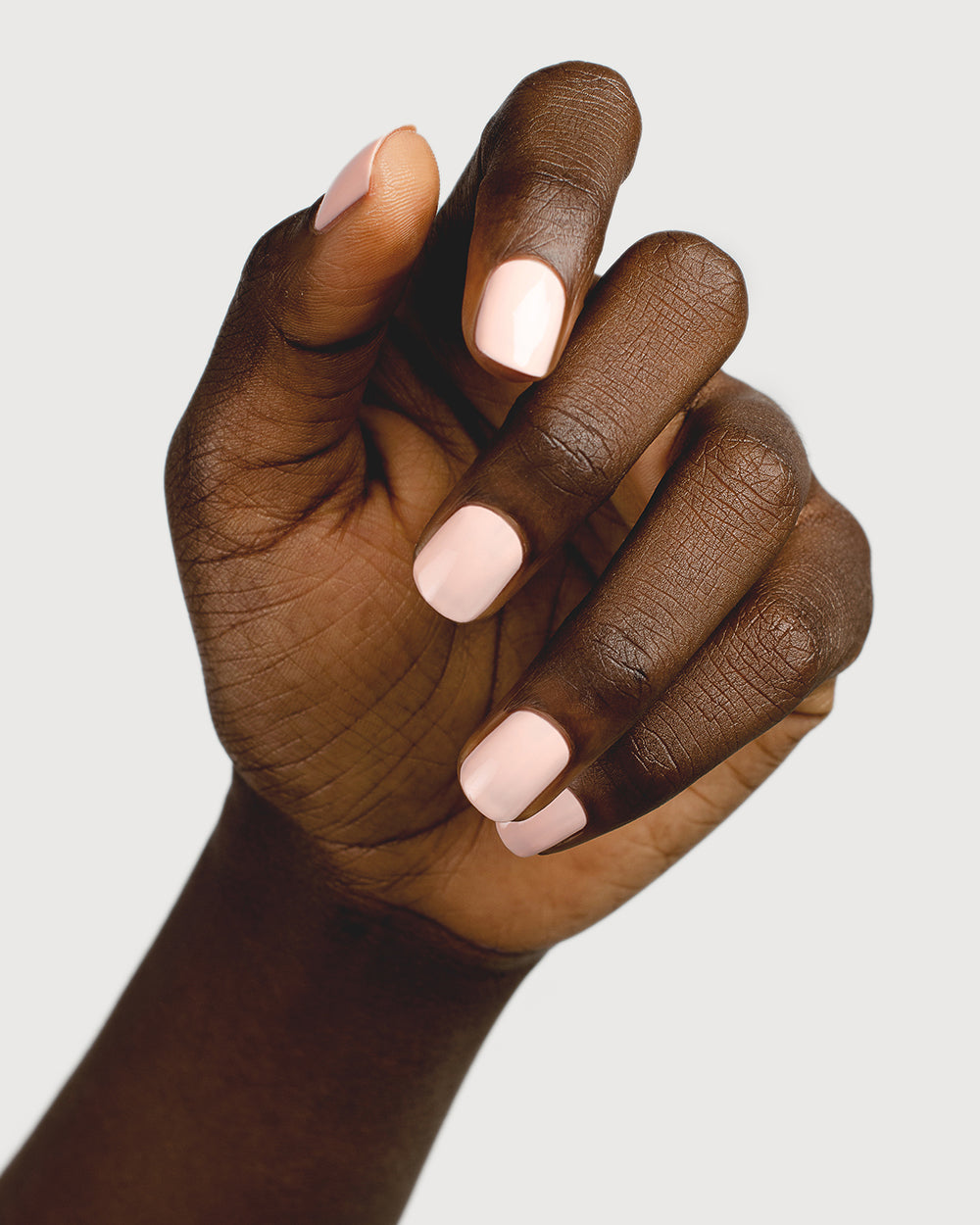 pastel pink nail polish hand swatch on dark skin tone