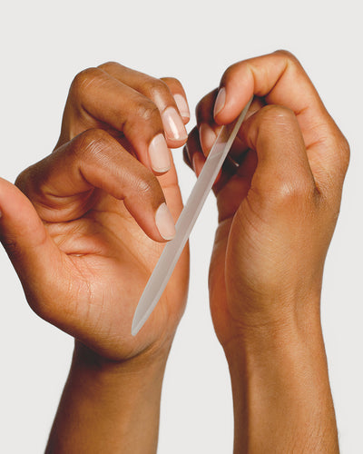 person filing nails with a glass nail file 