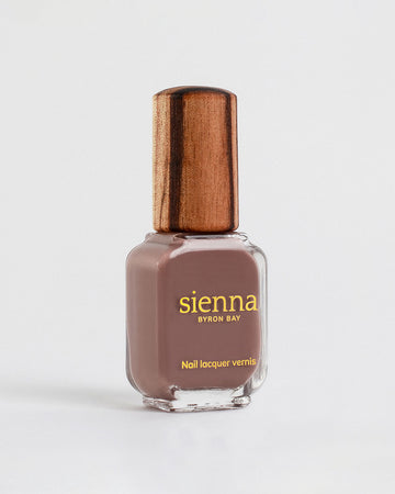 Grounded mylk chocolate crème Sienna nail polish bottles with gold logo and timber lids on a light grey-cream background.
