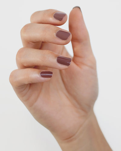 Fair skin hand wearing Grounded mylk chocolate crème nail polish by Sienna Byron Bay