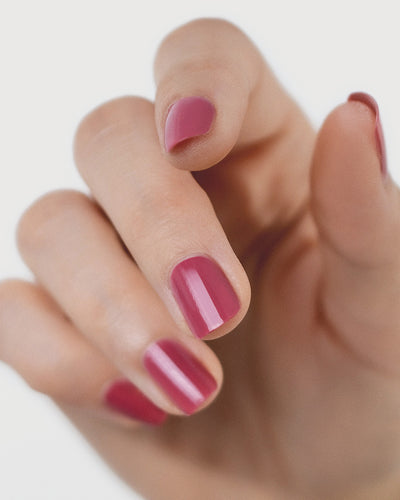 Fair skin hand wearing Heartspace raspberry sorbet nail polish by Sienna Byron Bay close-up