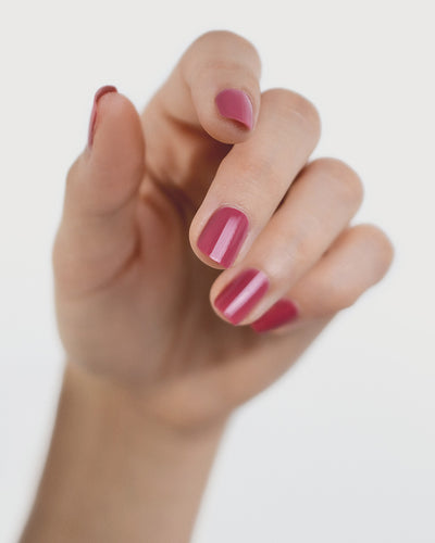 Fair skin hand wearing Heartspace raspberry sorbet nail polish by Sienna Byron Bay