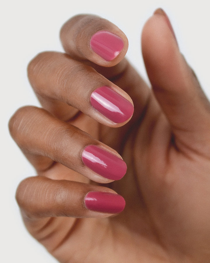 Medium tanned skin hand wearing Heartspace raspberry sorbet nail polish by Sienna Byron Bay close-up