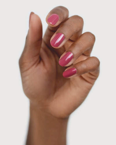 Medium tanned skin hand wearing Heartspace raspberry sorbet nail polish by Sienna Byron Bay