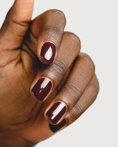 Aubergine nail polish hand swatch on dark skin tone up-close