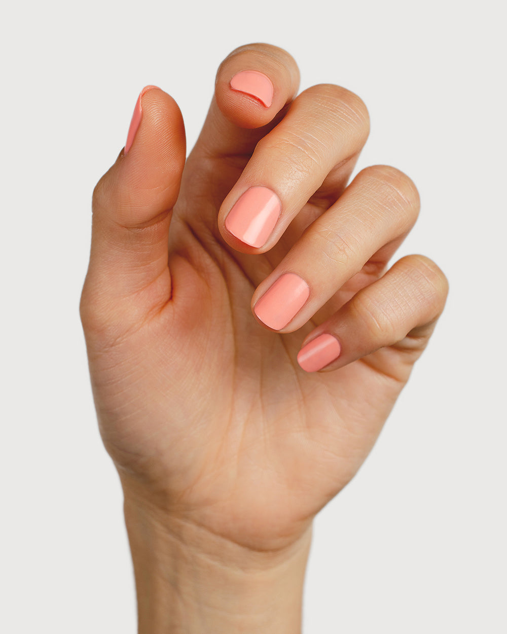 Vibrant peach nail polish hand swatch on fair skin tone