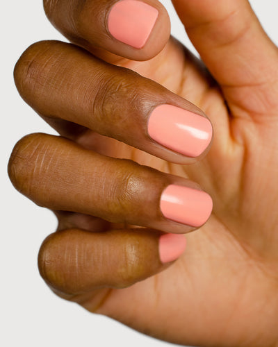 Vibrant peach nail polish hand swatch on medium skin tone up- close