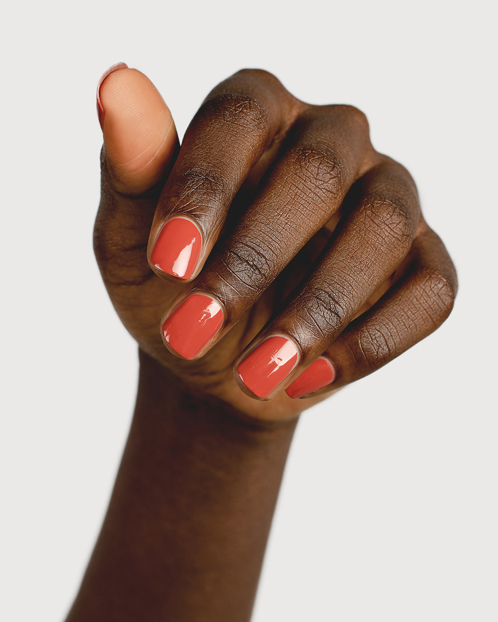 brick red nail polish hand swatch on dark skin tone 