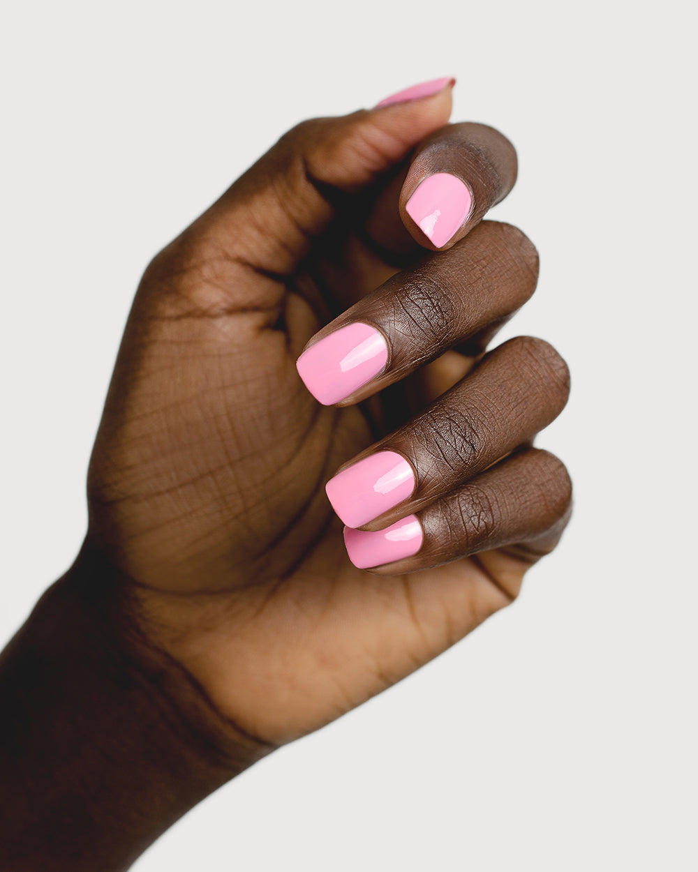 Classic lolly pink nail polish hand swatch on dark skin tone