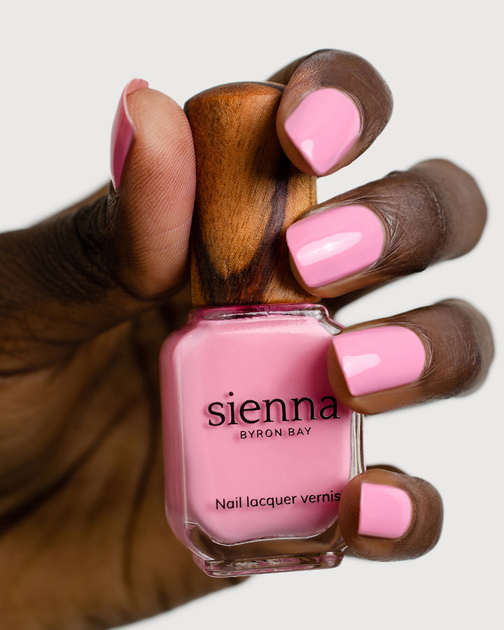 classic lolly pink nail polish hand swatch on dark skin tone holding sienna bottle