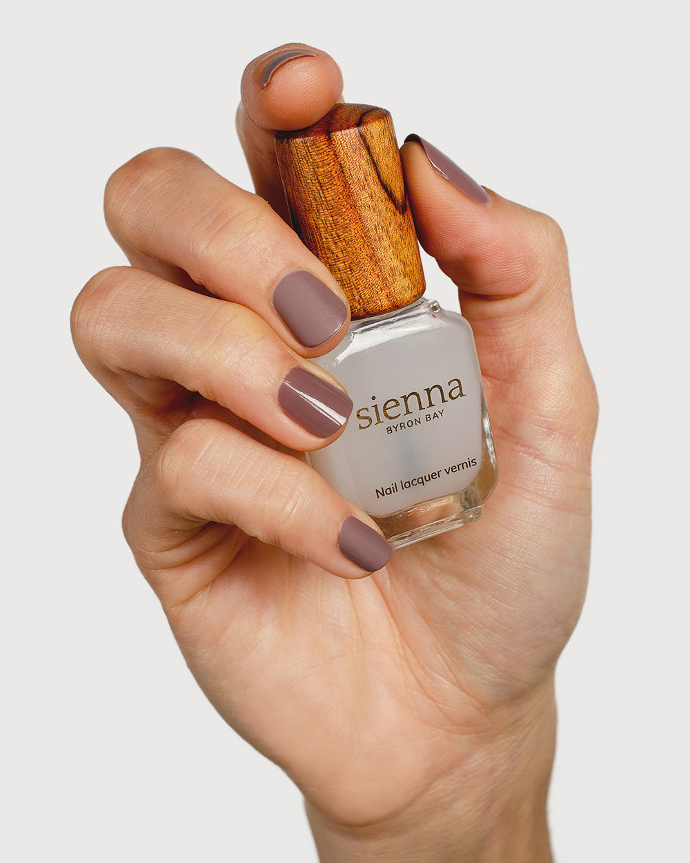 clear matte top coat nail polish hand swatch on fair skin tone holding sienna bottle
