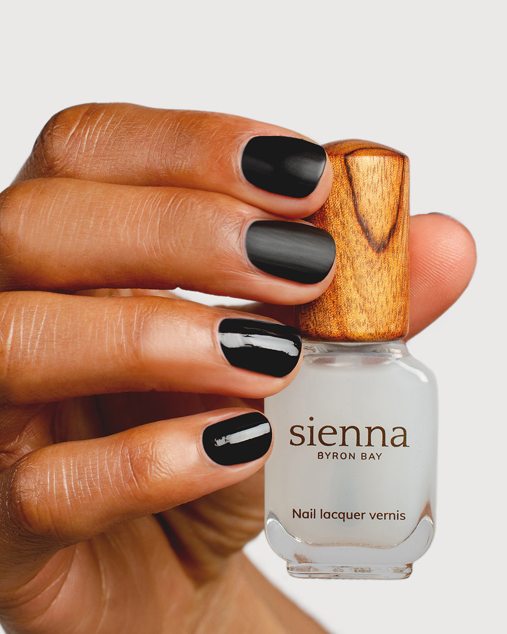 clear matte top coat nail polish hand swatch on medium skin tone holding sienna bottle
