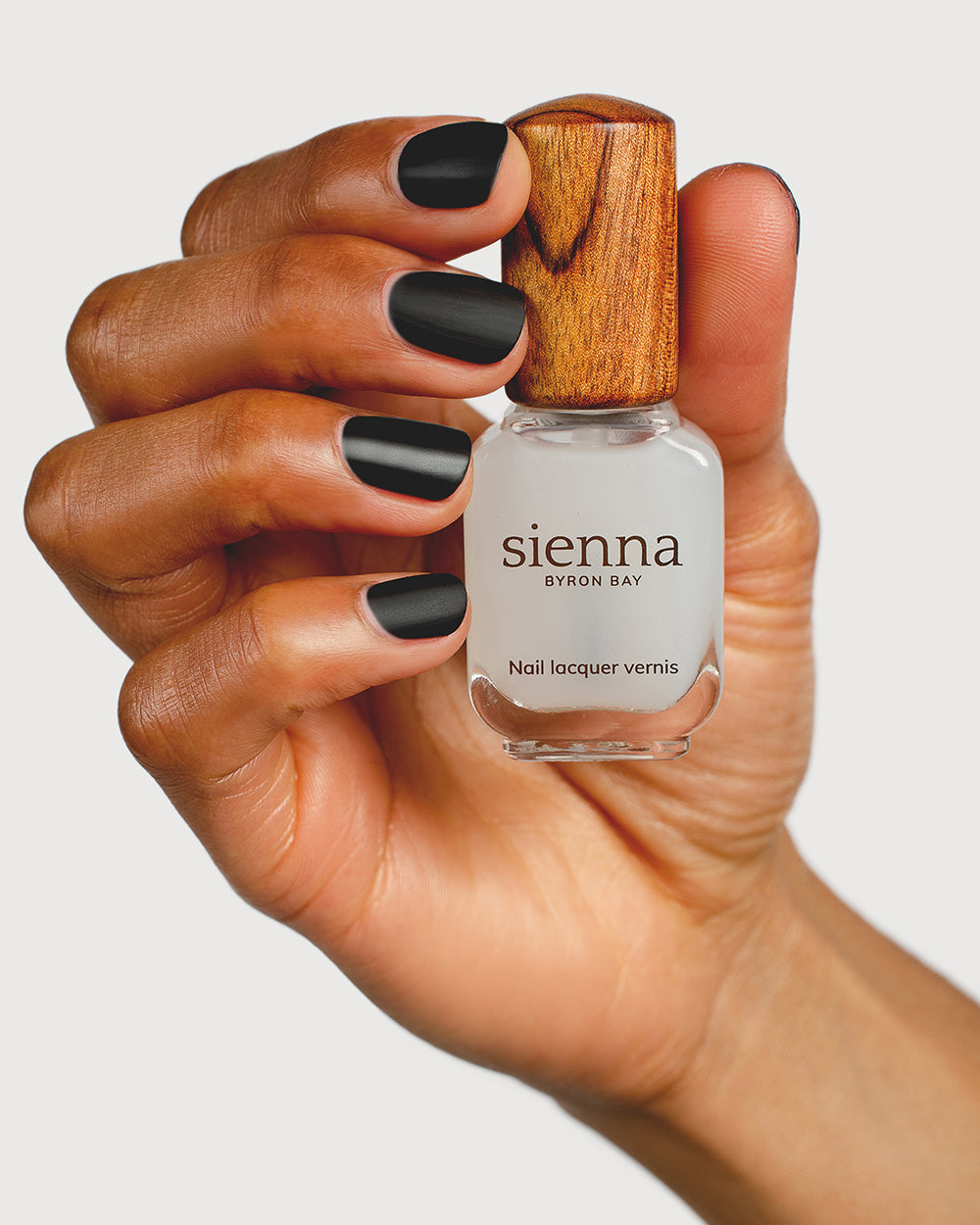 clear matte top coat nail polish hand swatch on medium skin tone holding sienna bottle