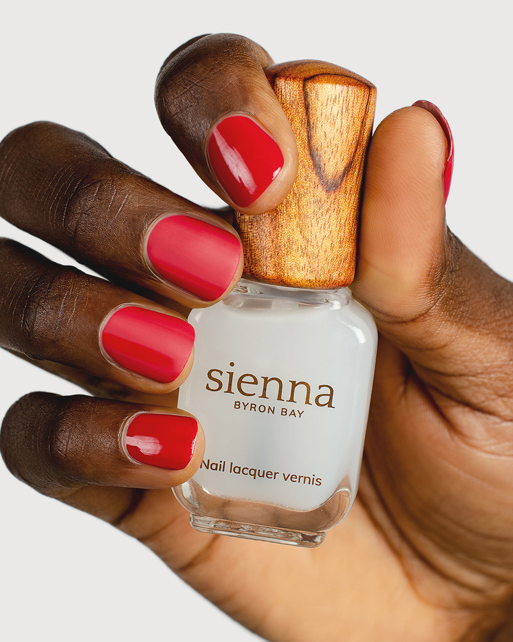 clear matte top coat nail polish hand swatch on dark skin tone holding sienna bottle