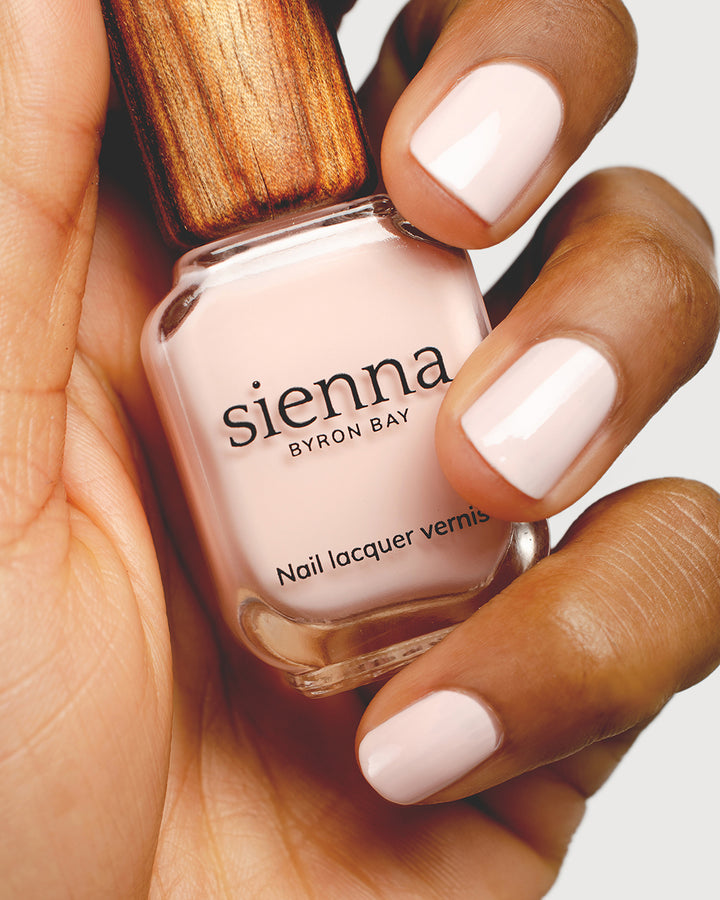 rosewater pink nail polish hand swatch on medium skin tone holding sienna bottle
