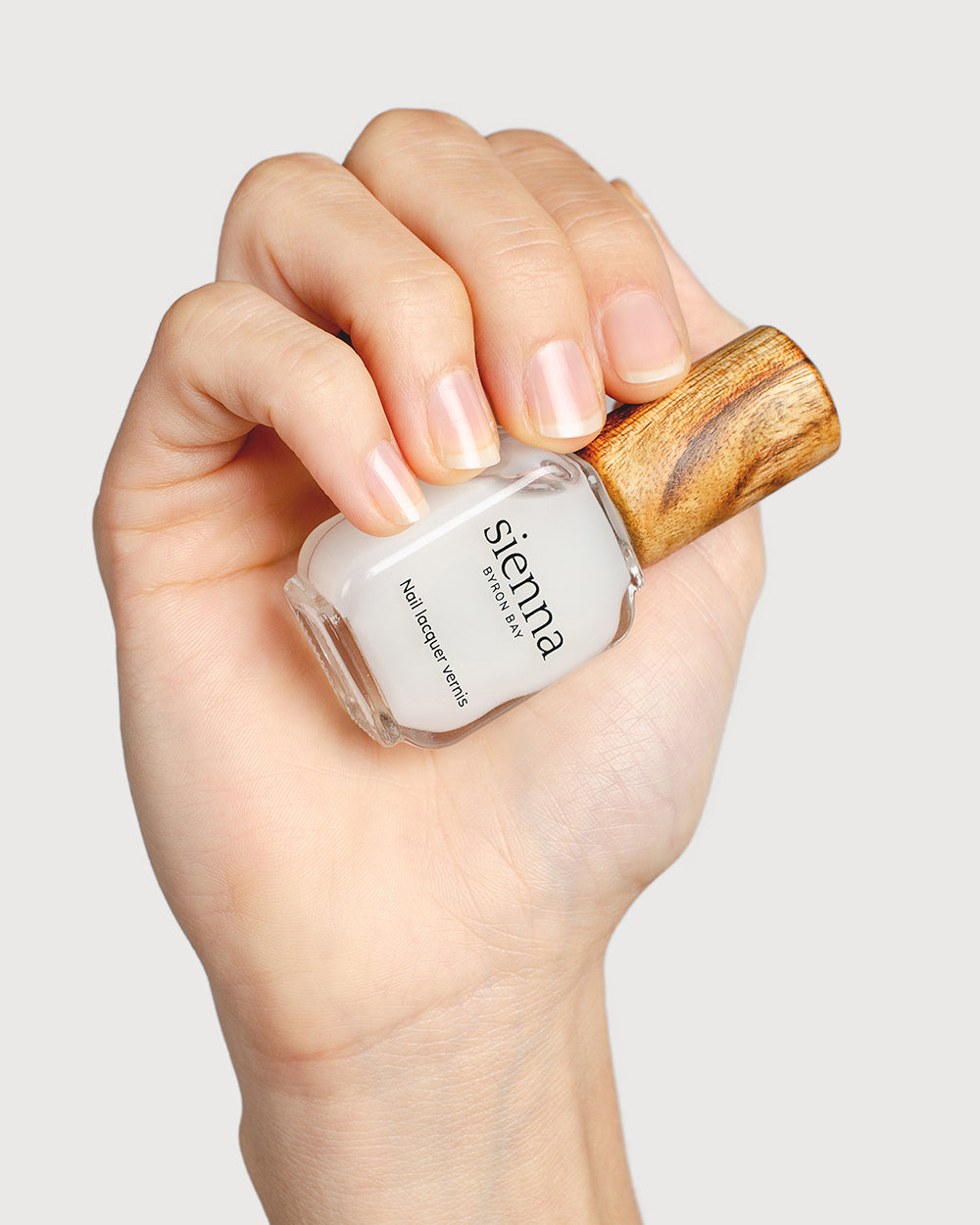 nail strengthener hand swatch on fair skin tone holding sienna bottle