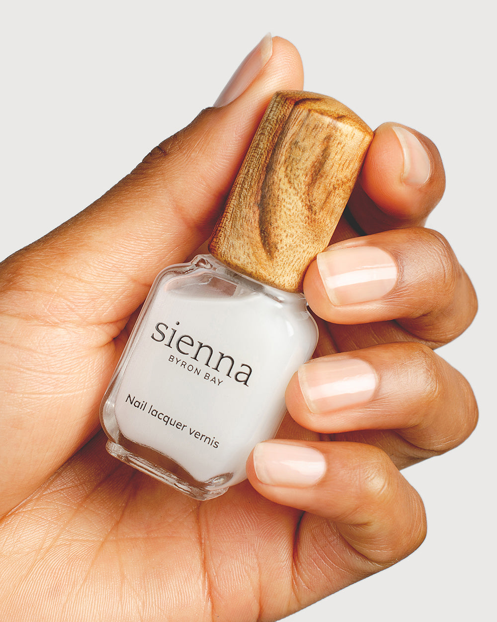 nail strengthener hand swatch on medium skin tone holding sienna bottle