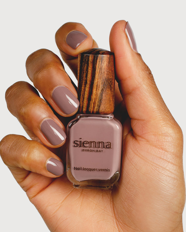 dusty mauve nail polish hand swatch on medium skin tone holding sienna bottle