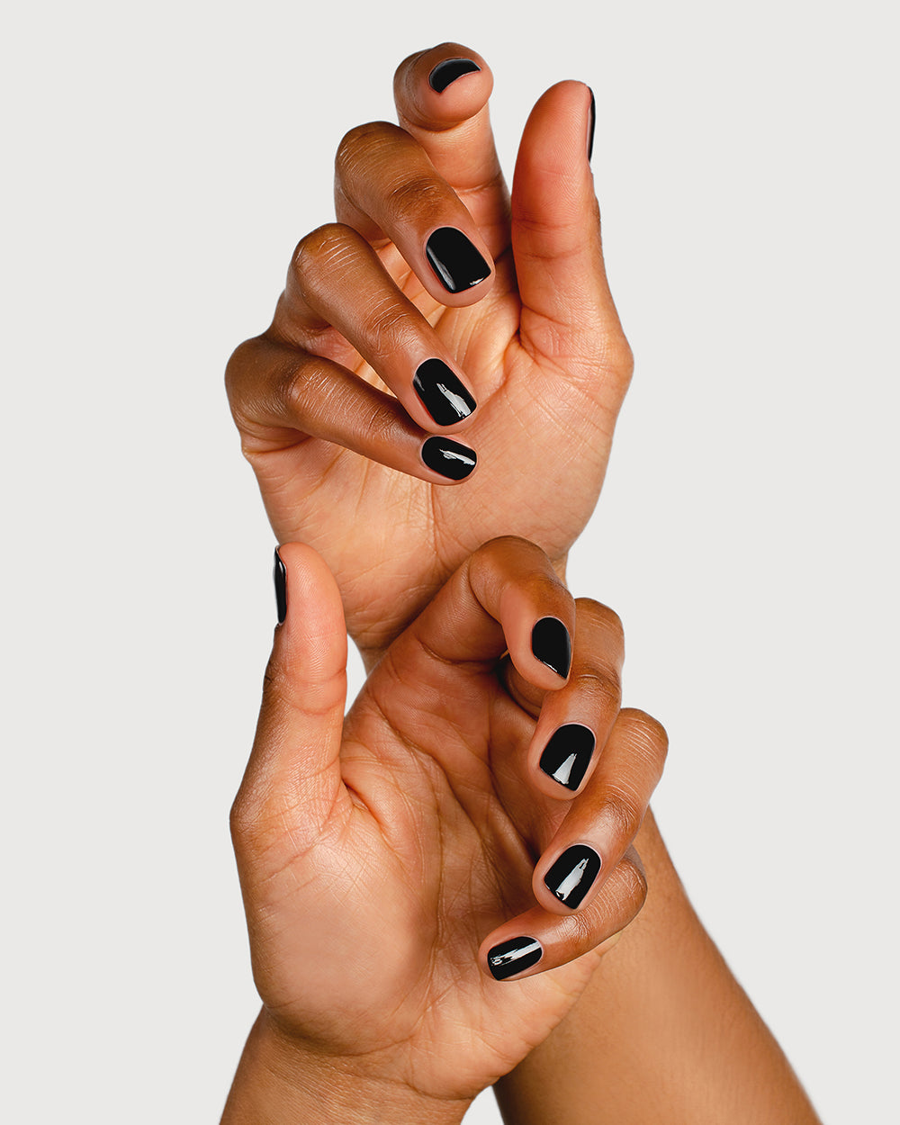 jet black nail polish hand swatch on medium skin tone, two hands, one above the other