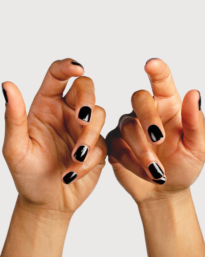 two hands wearing black nail polish on medium skin toned model