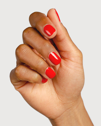 bright red nail polish hand swatch on medium skin tone