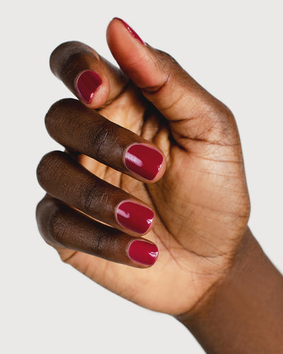 Plum red nail polish hand swatch on dark skin tone