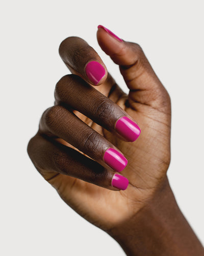 Bright magenta nail polish hand swatch on dark skin tone