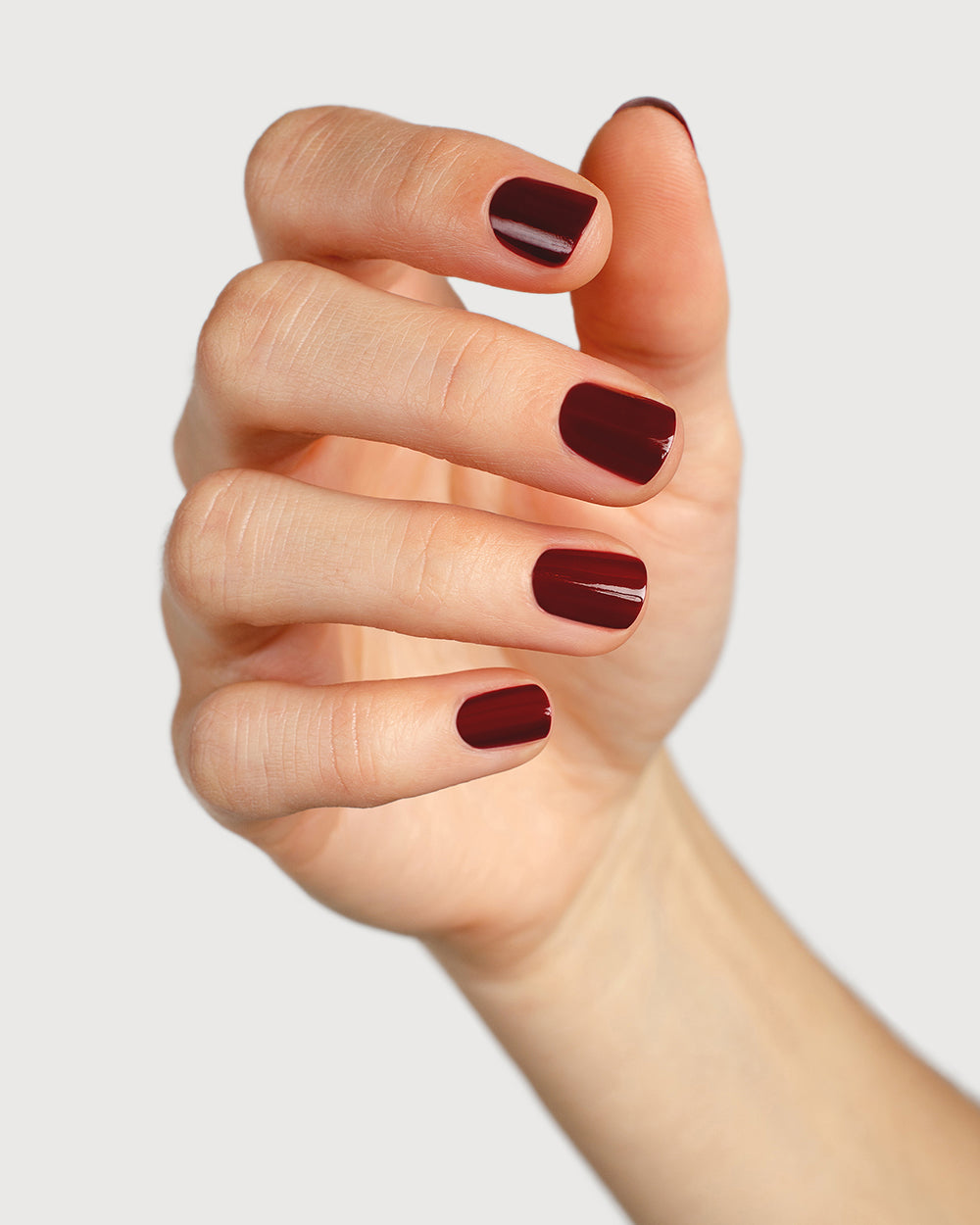 Organic mid-tone red nail polish hand swatch on fair skin tone