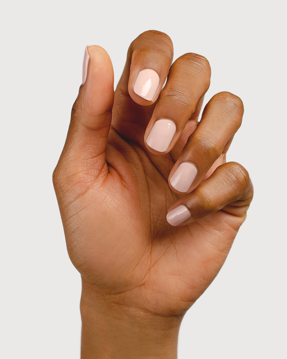 Light champagne pink nail polish hand swatch on medium skin tone