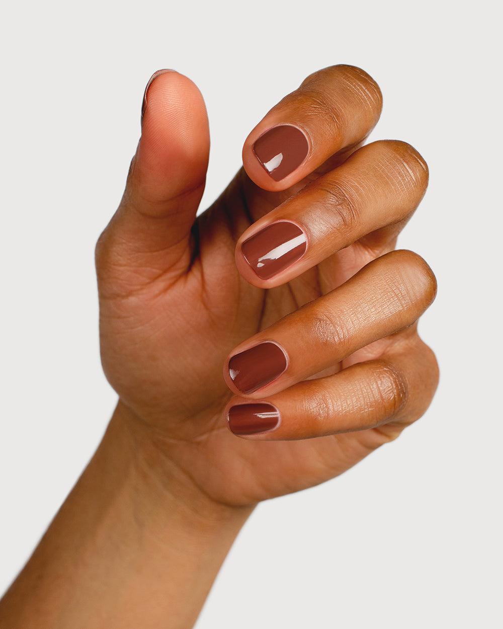 brown nail polish hand swatch on medium skin tone