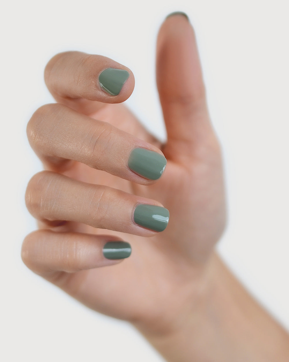 Fair skin hand wearing Soundscape sage green crème nail polish by Sienna Byron Bay