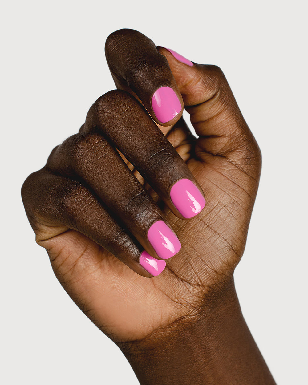Bright mid-tone fuchsia nail polish hand swatch on dark skin tone