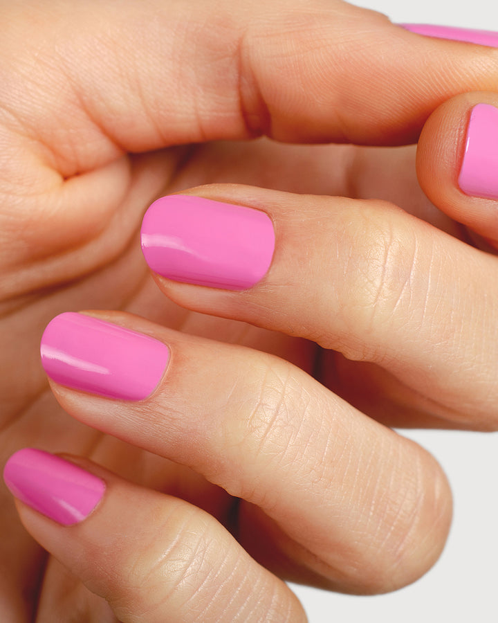 Bright mid-tone fuchsia nail polish hand swatch on fair skin tone up close