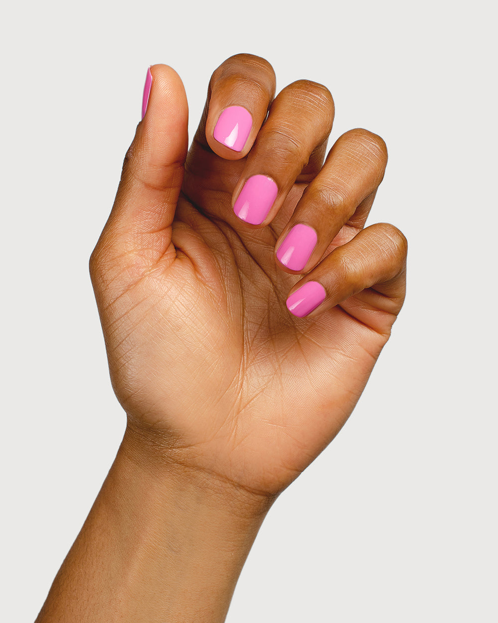 Bright mid-tone fuchsia nail polish hand swatch on medium skin tone