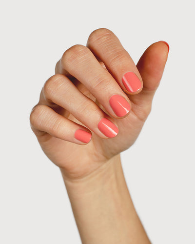 Pink peach nail polish hand swatch on fair skin tone