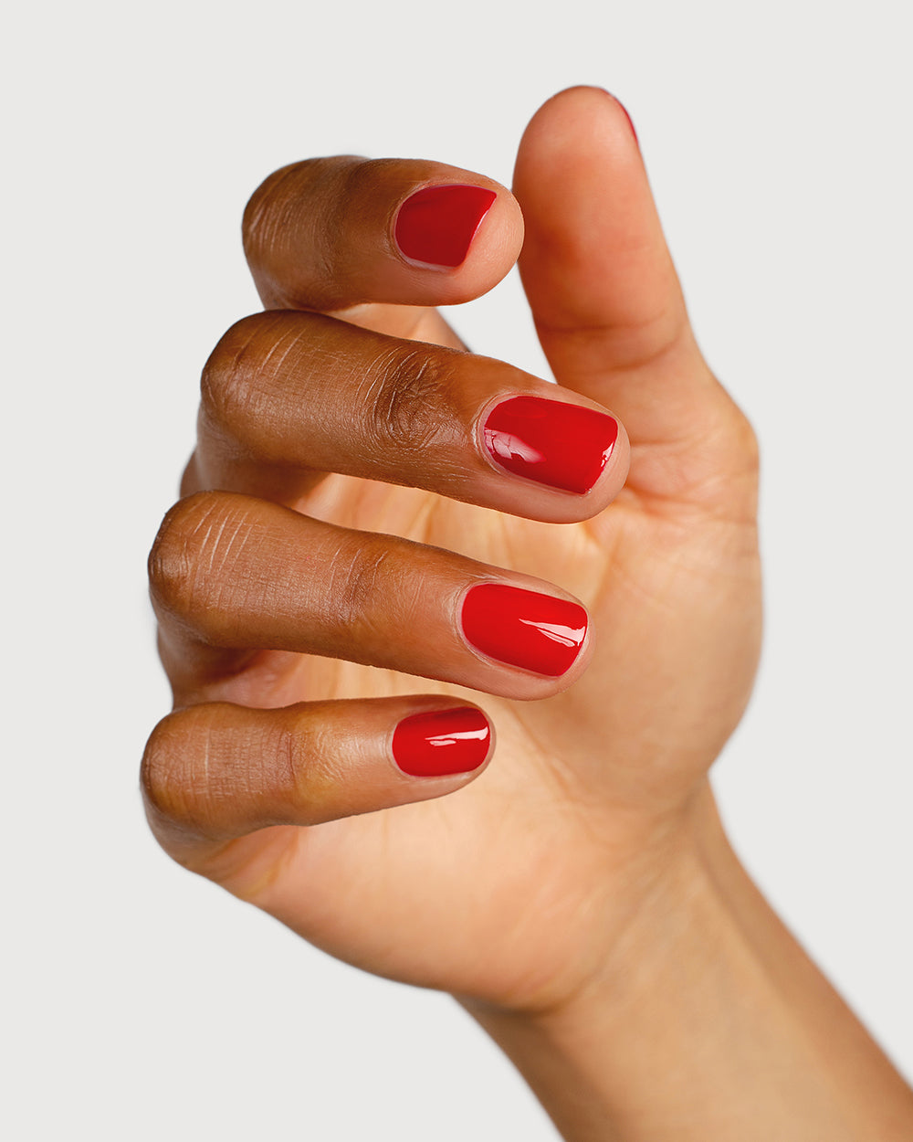 Classic red nail polish hand swatch on medium skin tone