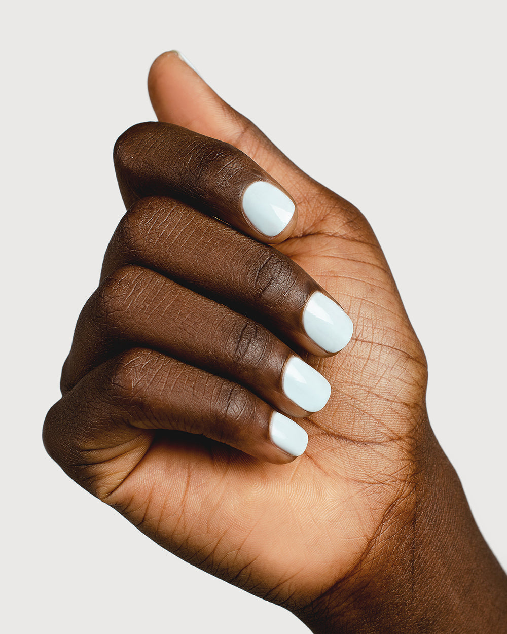 Pastel blue nail polish hand swatch on dark skin tone