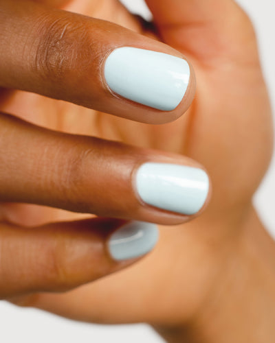 Pastel blue nail polish hand swatch on medium skin tone close-up