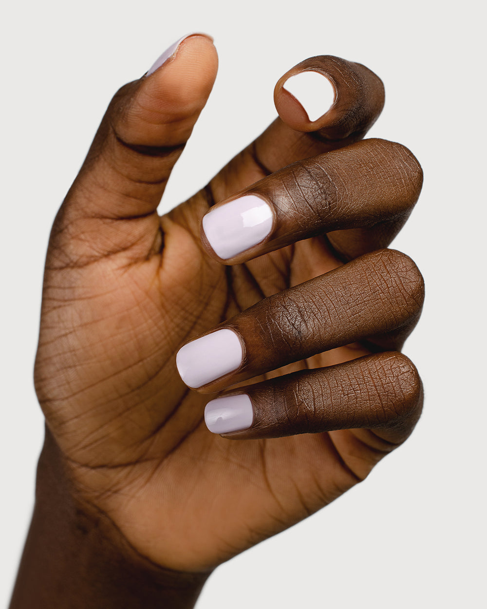Light lilac pastel nail polish hand swatch on dark skin tone