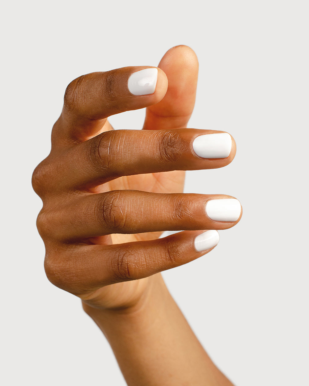 Crisp snow white nail polish hand swatch on medium skin tone